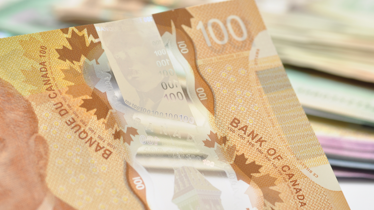 Un billet de 100 $ devant une pile d'autres billets d'argent.