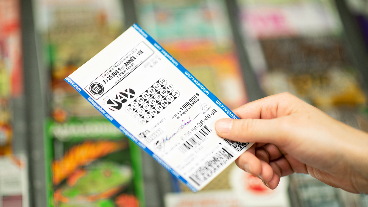 Un billet de Lotto Max dans une main.