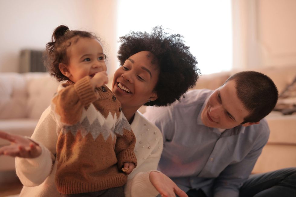 Un couple souriant avec leur jeune enfant.