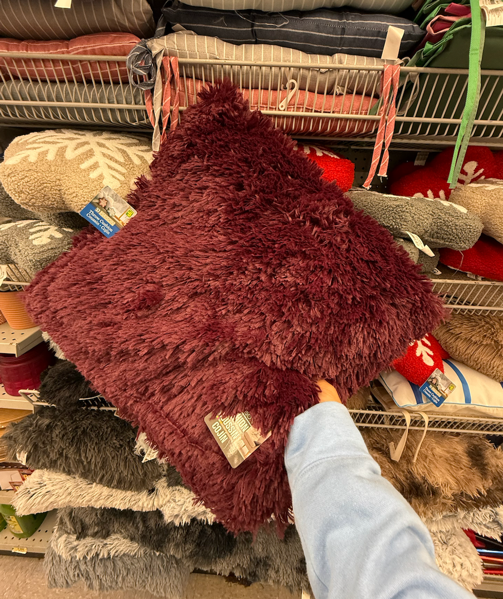Un coussin bourgogne en fausse fourrure pr\u00e9sent\u00e9 dans le rayon des textiles du Dollarama.