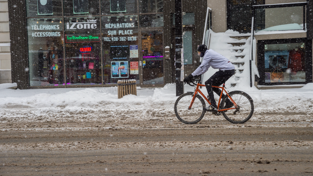 Un cycliste sous la neige sur un boulevard de Montréal.