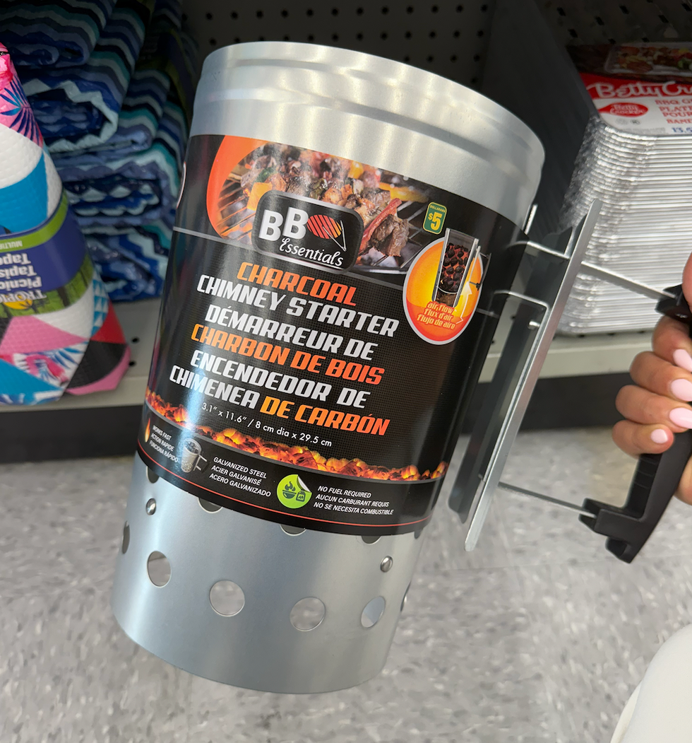 Un cylindre m\u00e9tallique avec poign\u00e9e noire utilis\u00e9 pour allumer du charbon.