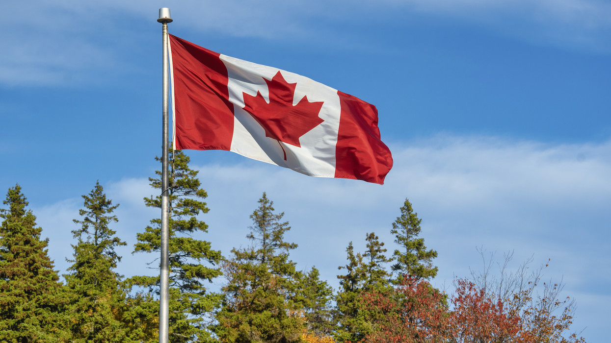 Un drapeau du Canada devant des arbres l'automne.