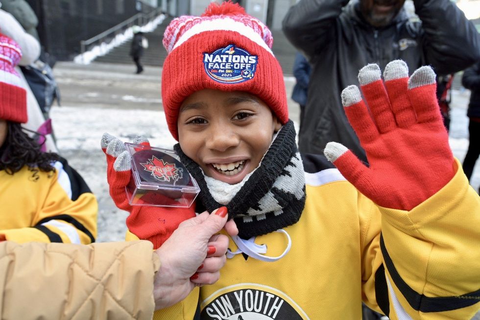 Un.e jeune fan de hockey sourit et pose avec une rondelle.