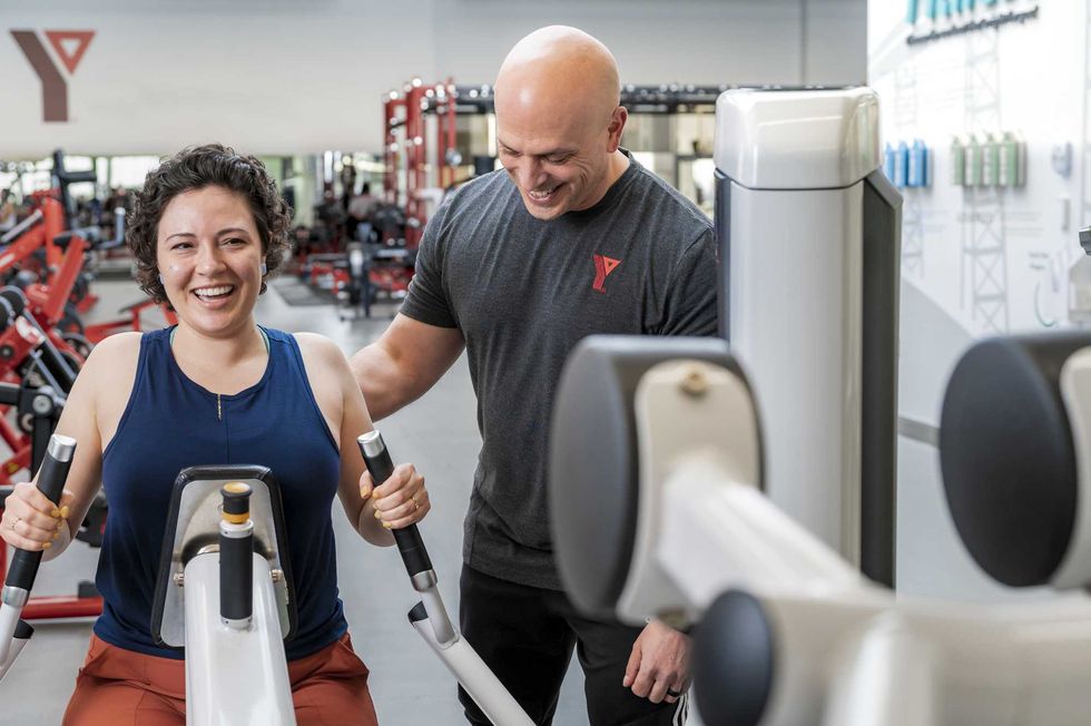 Un entra\u00eeneur du YMCA avec un membre dans l\u2019espace de musculation.