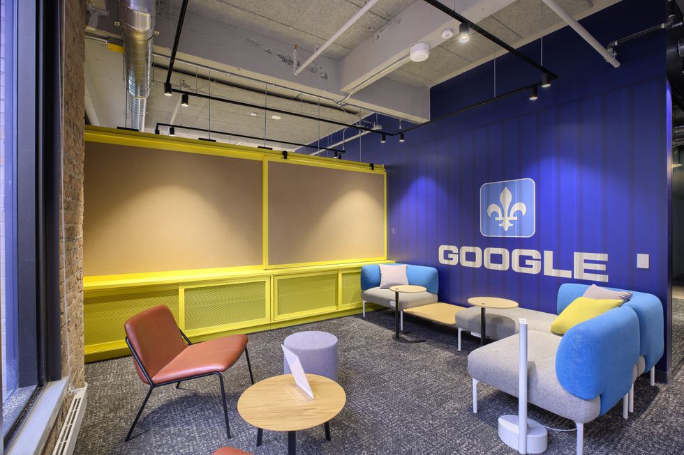 Un espace de travail avec un mur bleu o\u00f9 il est inscrit Google avec logo de la fleur de lys.