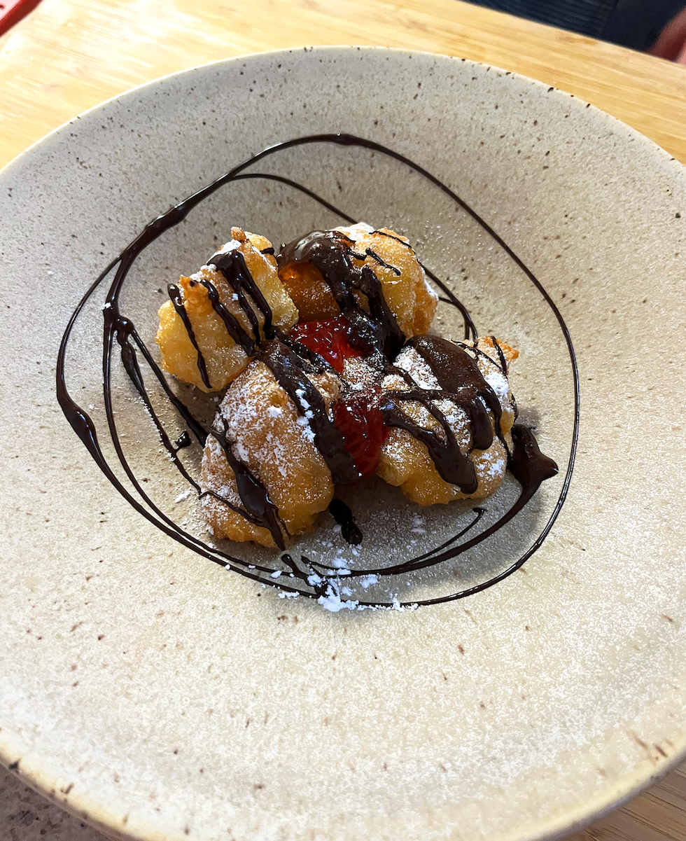 Un grand bol avec des beignets frits, de la garniture au chocolat et de la confiture de fraises.