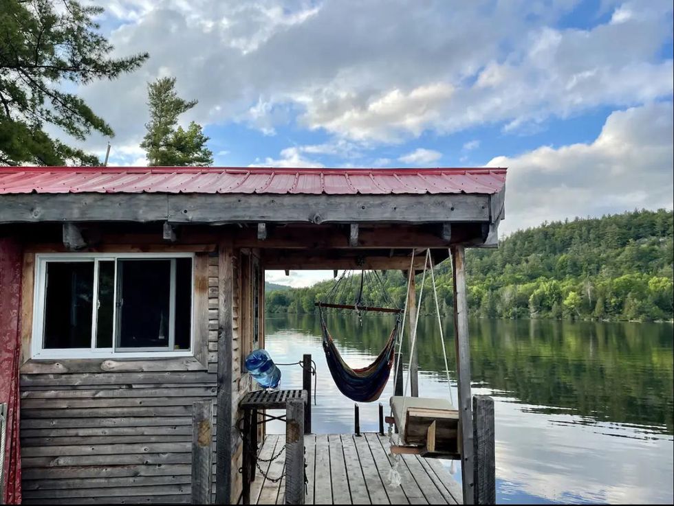 Un hamac et un lit suspendus sur la terrasse de la cabane sur l'eau, avec vue des montagnes et de l'eau.