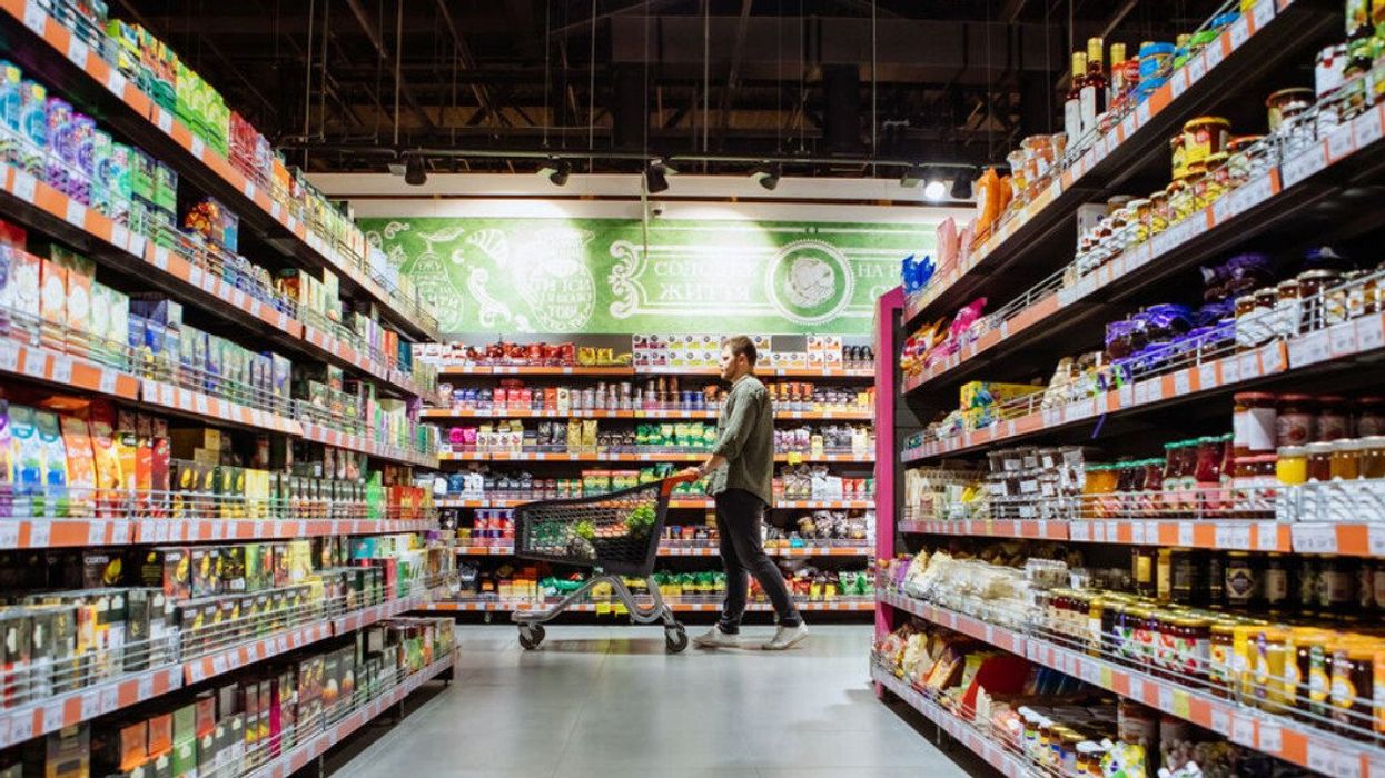 Un homme avec un panier dans une allée d'épicerie.