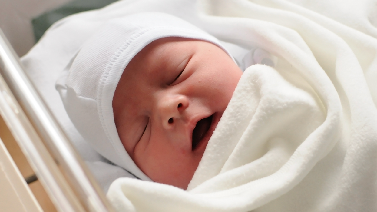 Un nouveau-né la bouche ouverte dans un petit lit à l'hôpital.