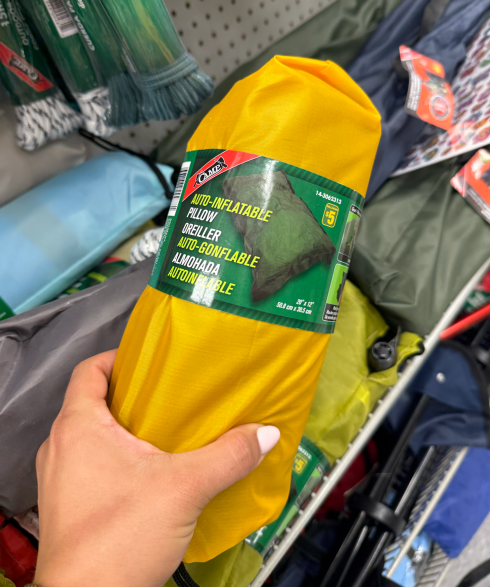 Un oreiller auto-gonflable roul\u00e9 dans un tissu jaune vif, tenu \u00e0 la main.