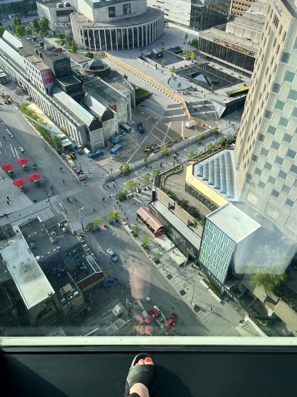 Un pied se trouve pr\u00e8s d'une grande fen\u00eatre avec une vue surplombant le centre-ville de Montr\u00e9al.