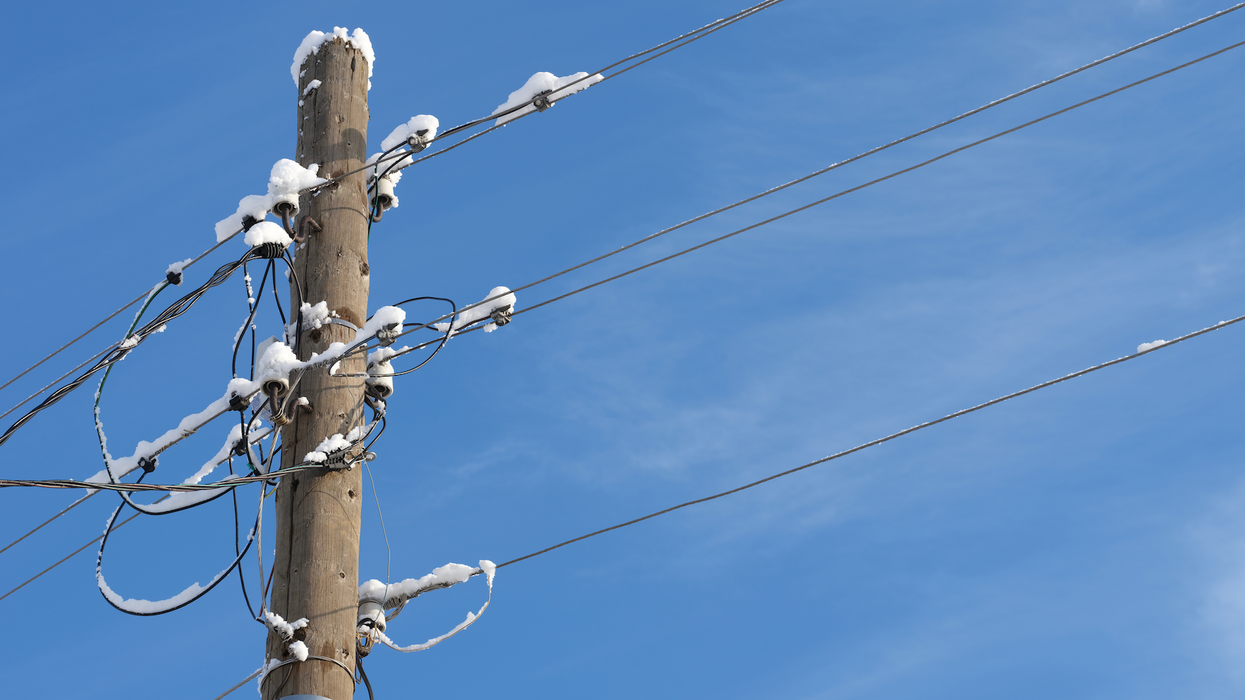 Un poteau électrique et des fils recouverts de neige.