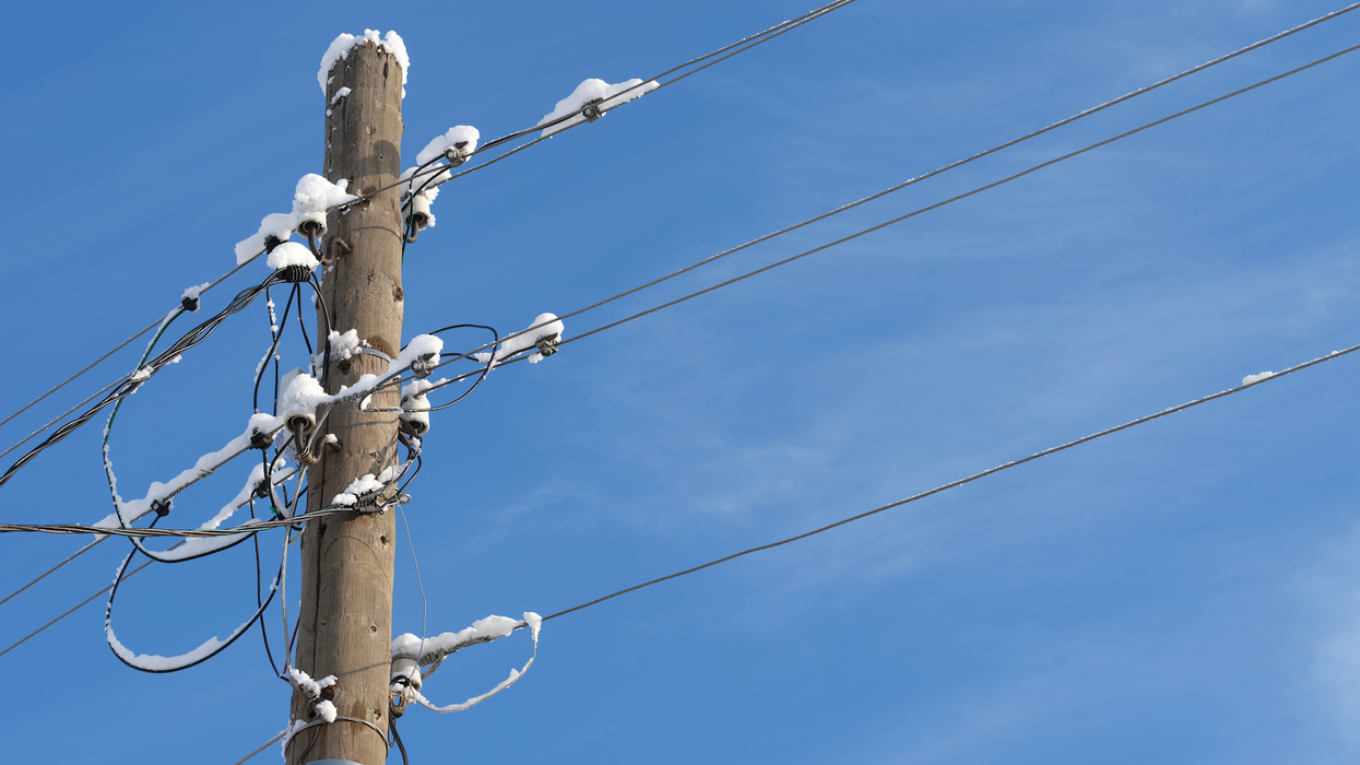 Un poteau électrique et des fils recouverts de neige.