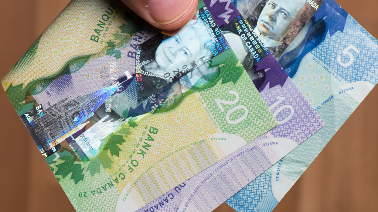 Un pouce devant des billets d'argent placés en éventail.