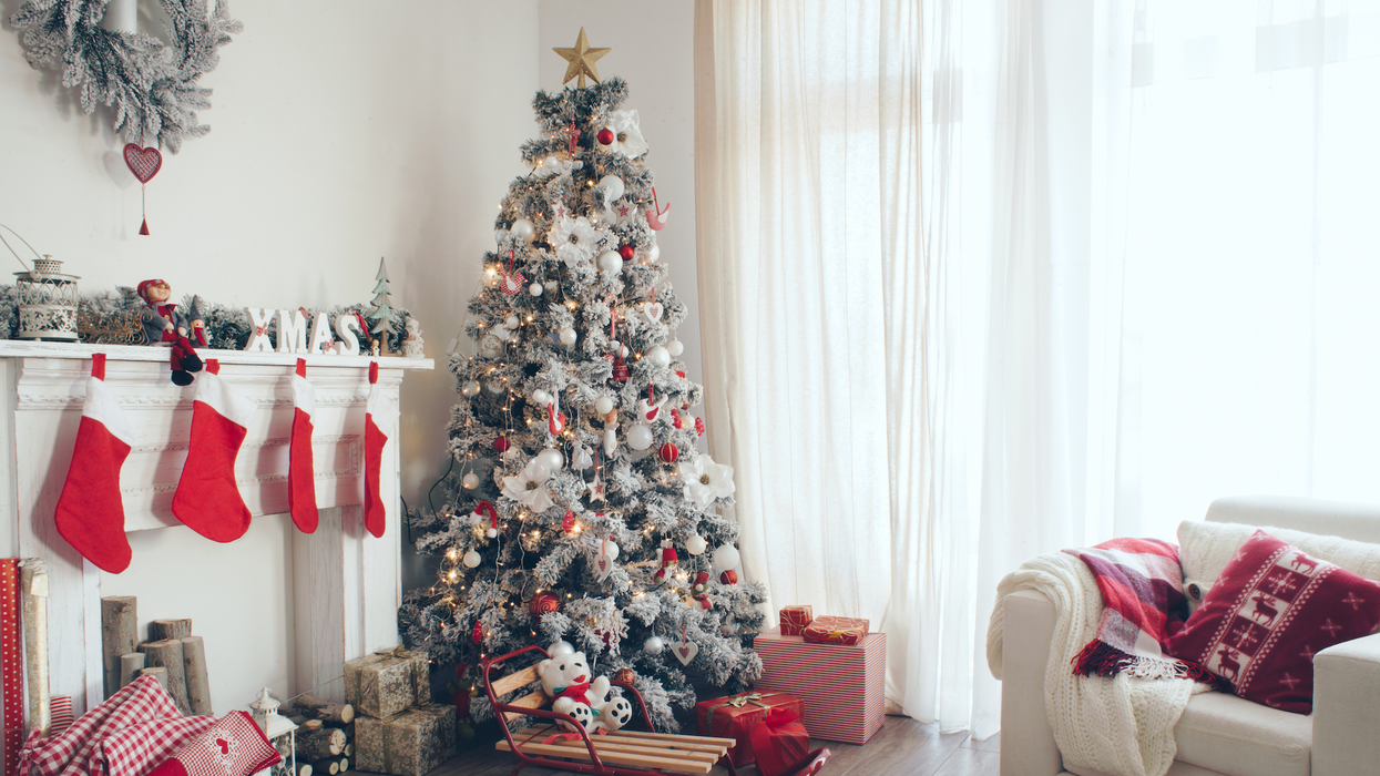 Un salon décoré pour Noël avec un sapin décoré de blanc et rouge, des bas, un divan.