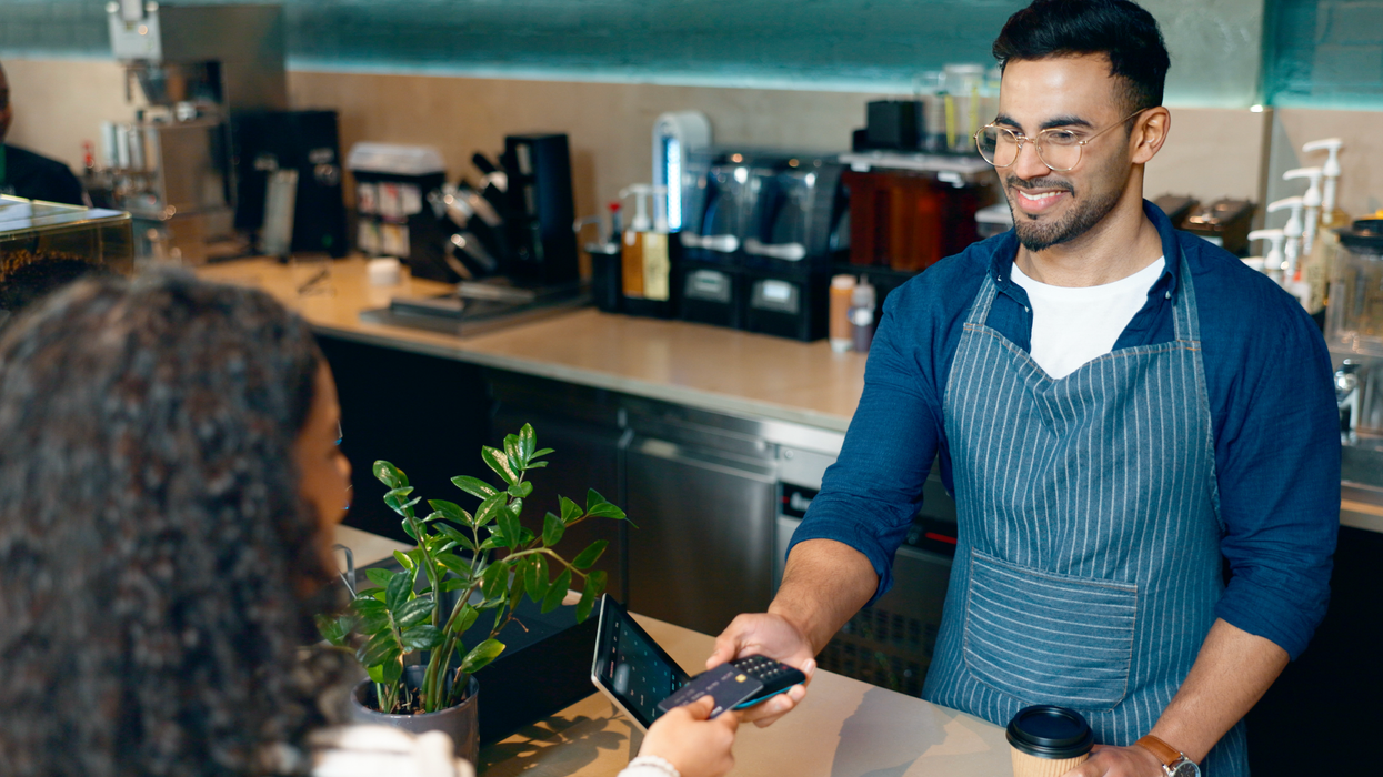 Un serveur fait payer une cliente avec une machine Interac dans un café.