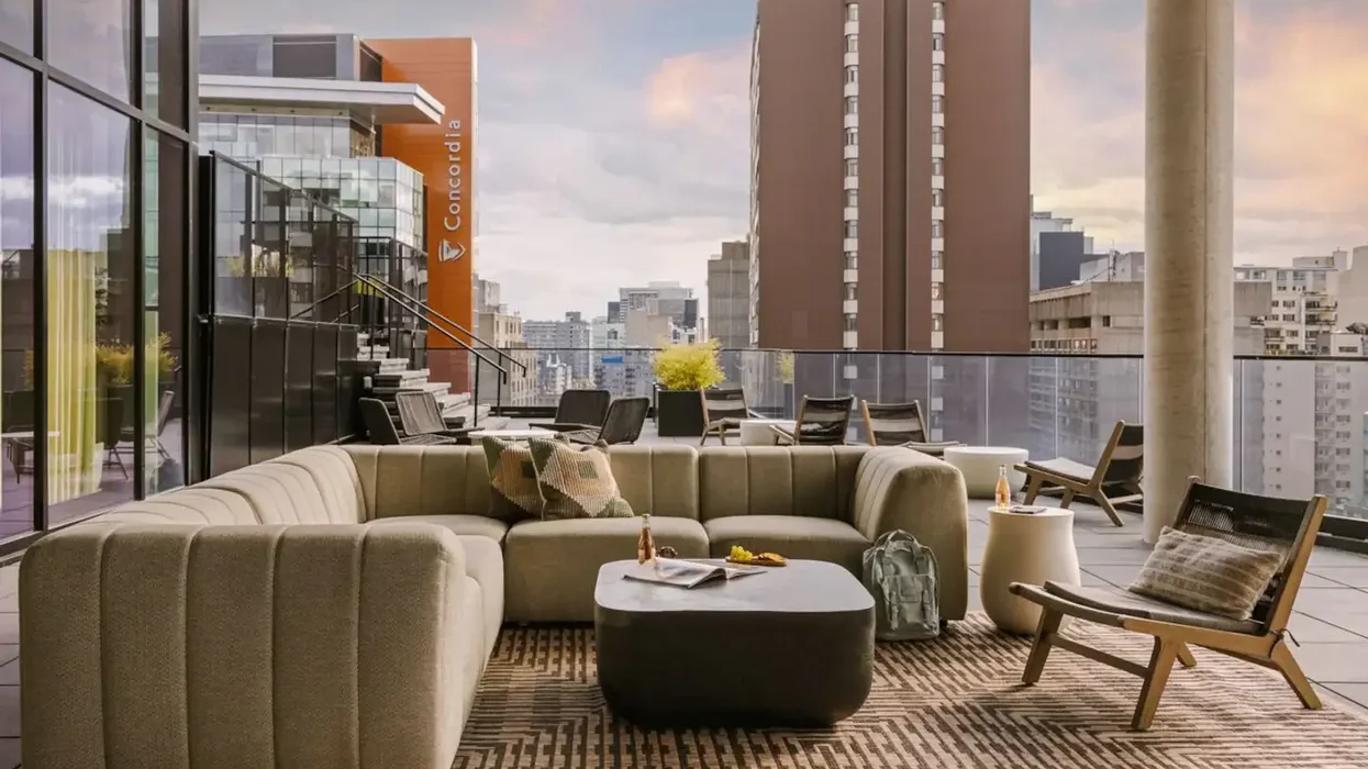 Un sofa extérieur avec une table et un tapis beige, vue sur la ville du balcon.
