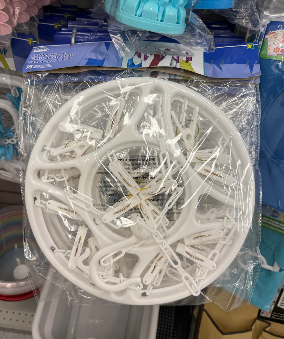 Un support circulaire blanc avec plusieurs pinces, dans son emballage de plastique transparent.