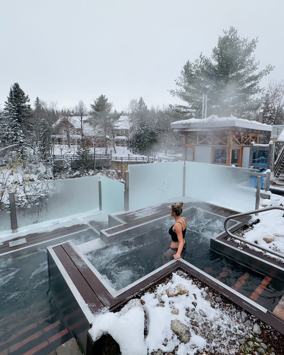 Un\u00b7e client\u00b7e entre dans l\u2019un des bains chauds d\u2019un spa nordique entour\u00e9 de neige.