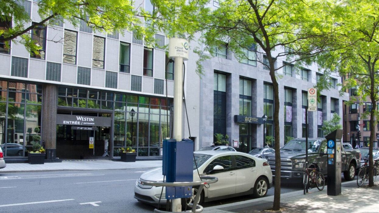 Un véhicule électrique est branché sur une borne de recharge du Circuit Électrique devant un hôtel à Montréal.