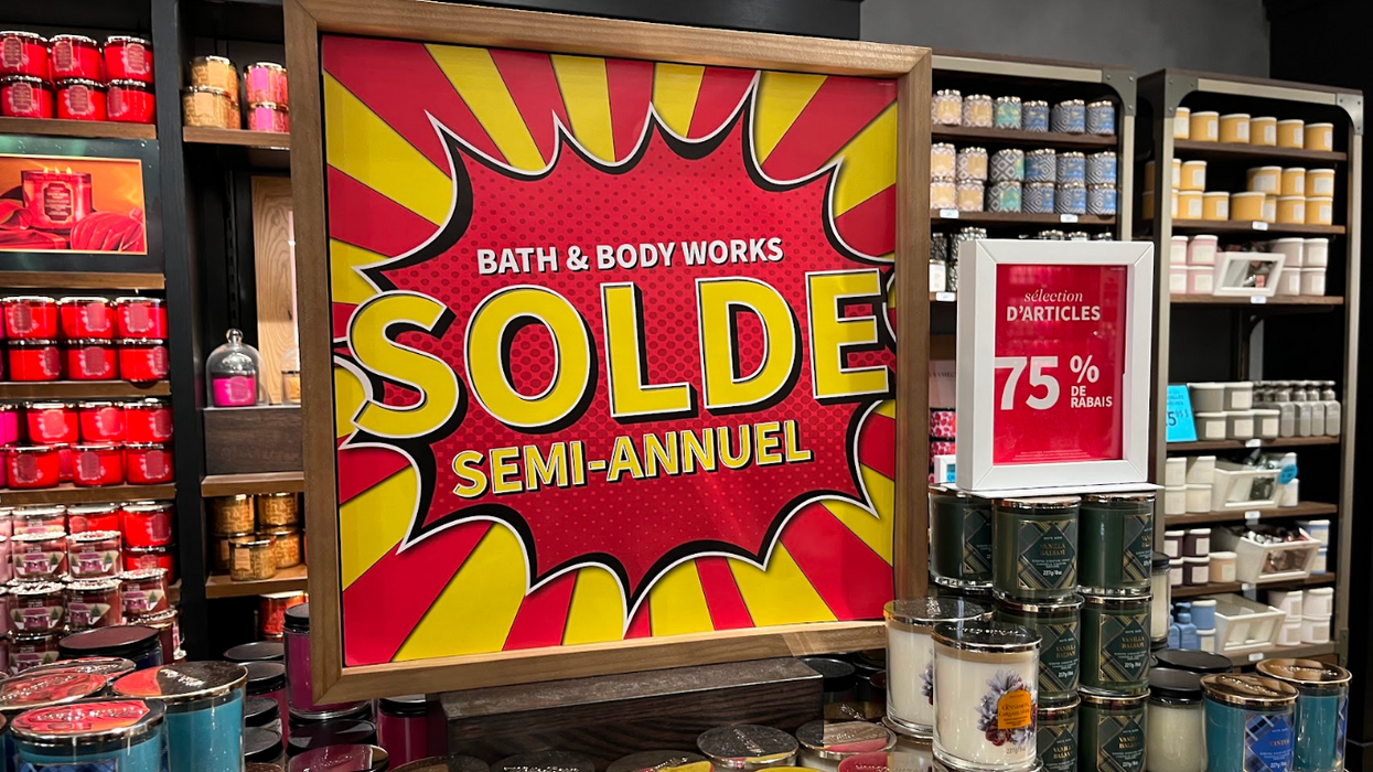 Une affiche du solde semi-annuel Bath & Body Works sur une pile de chandelles.