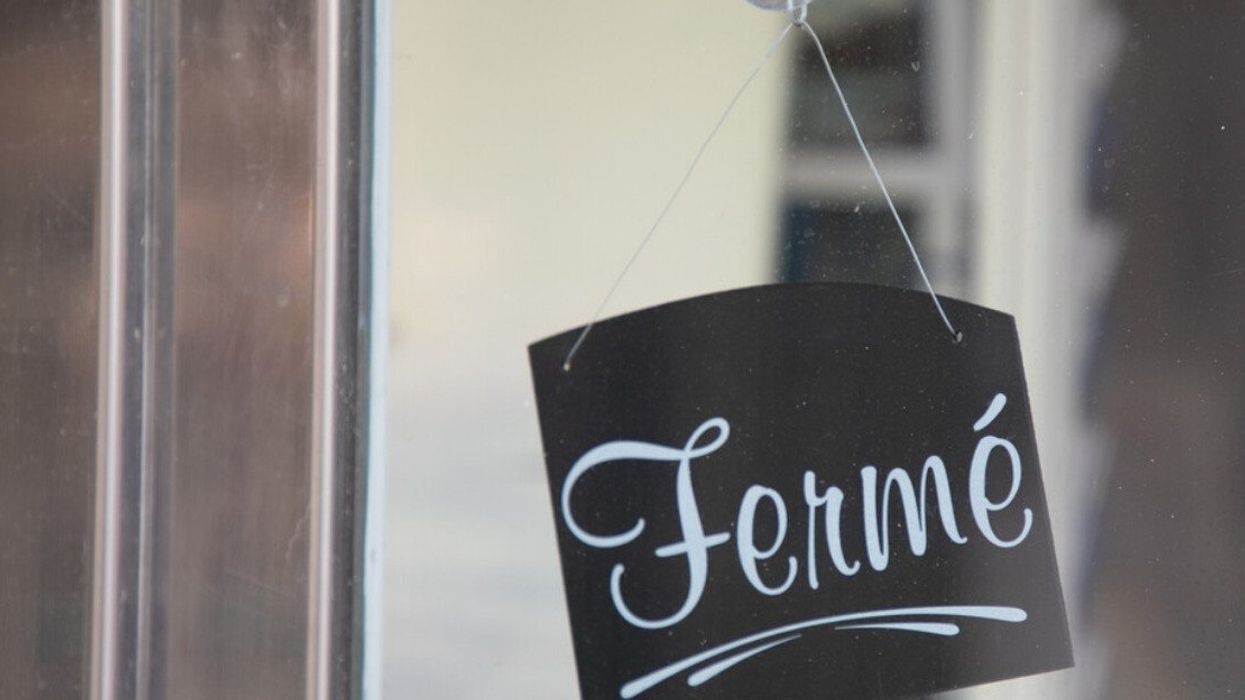 Une affiche où il est inscrit « fermé » est installée dans la fenêtre d'une portes.