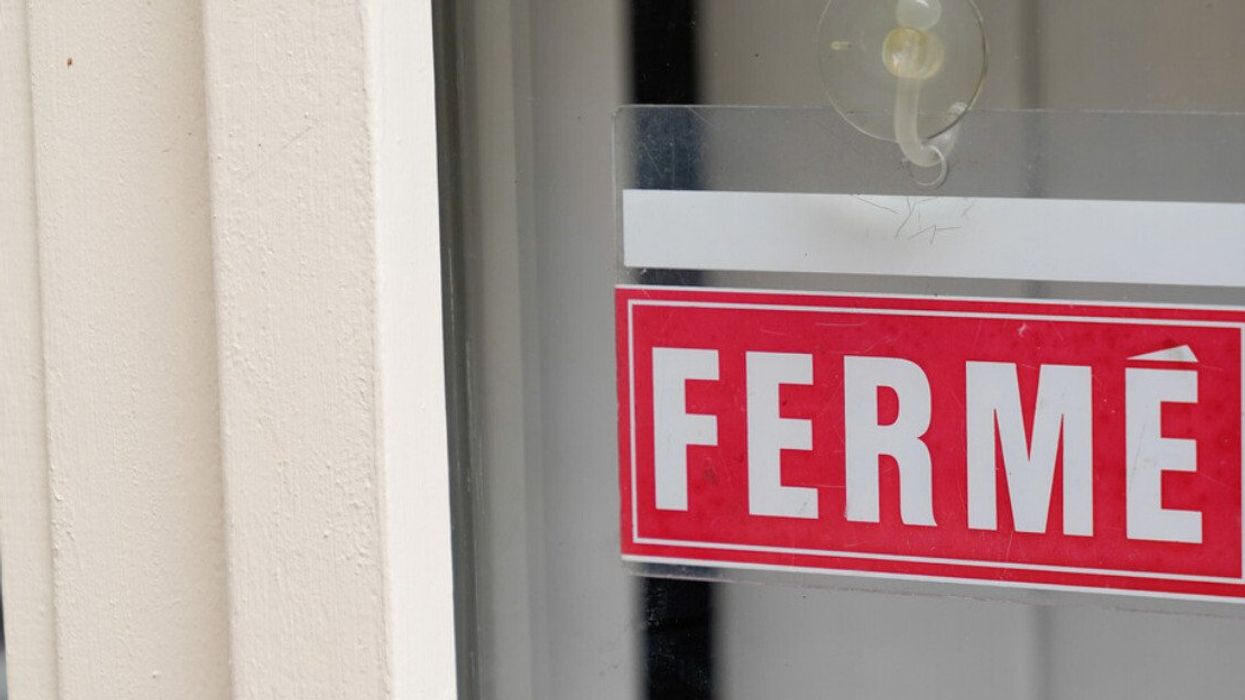 Une affiche rouge où il est écrit FERMÉ dans la fenêtre d'une porte.