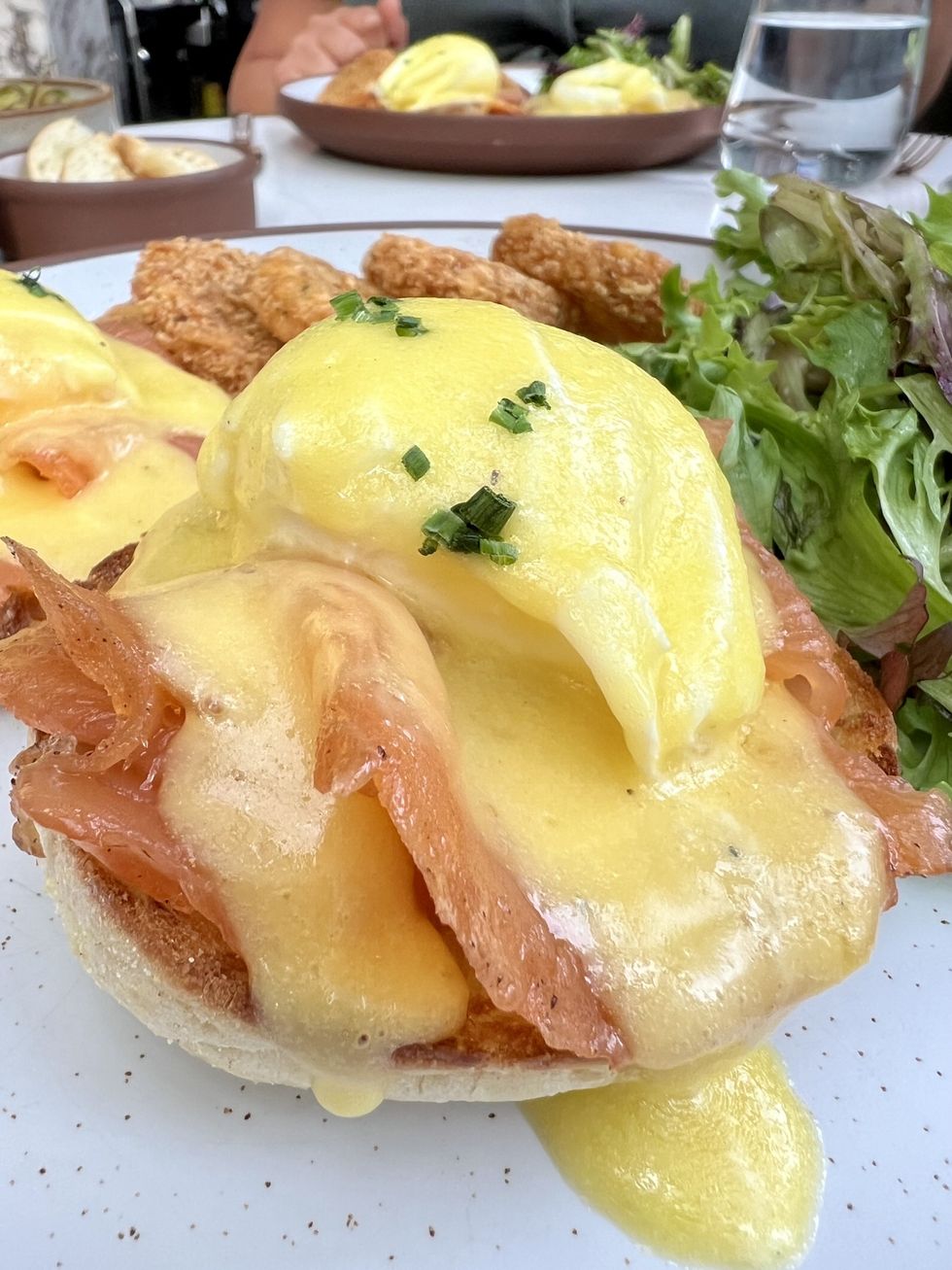 Une assiette avec des oeufs b\u00e9n\u00e9dictines au saumon recouvert d'une sauce hollandaise.