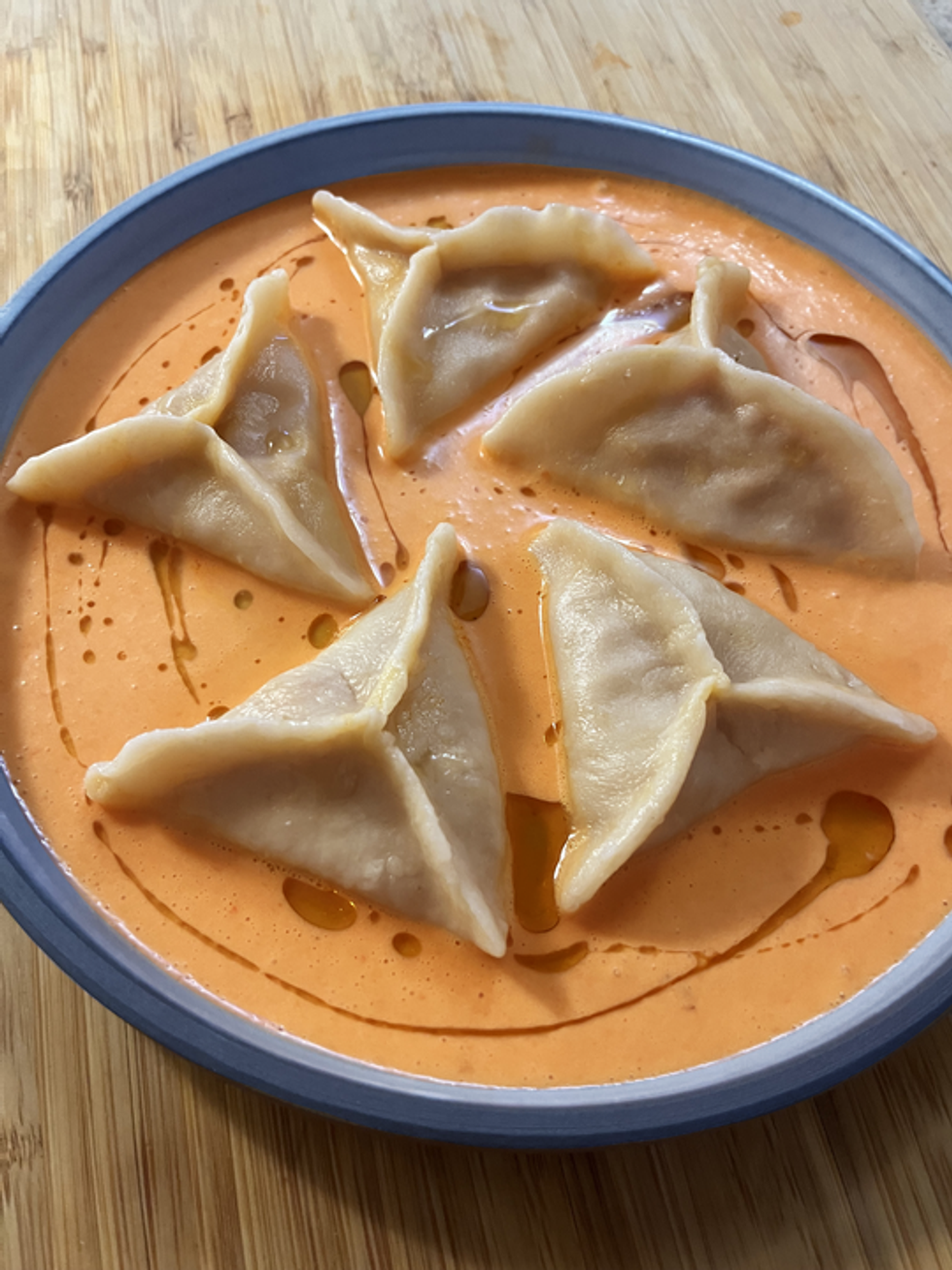 Une assiette de dumplings dans une sauce orang\u00e9e.