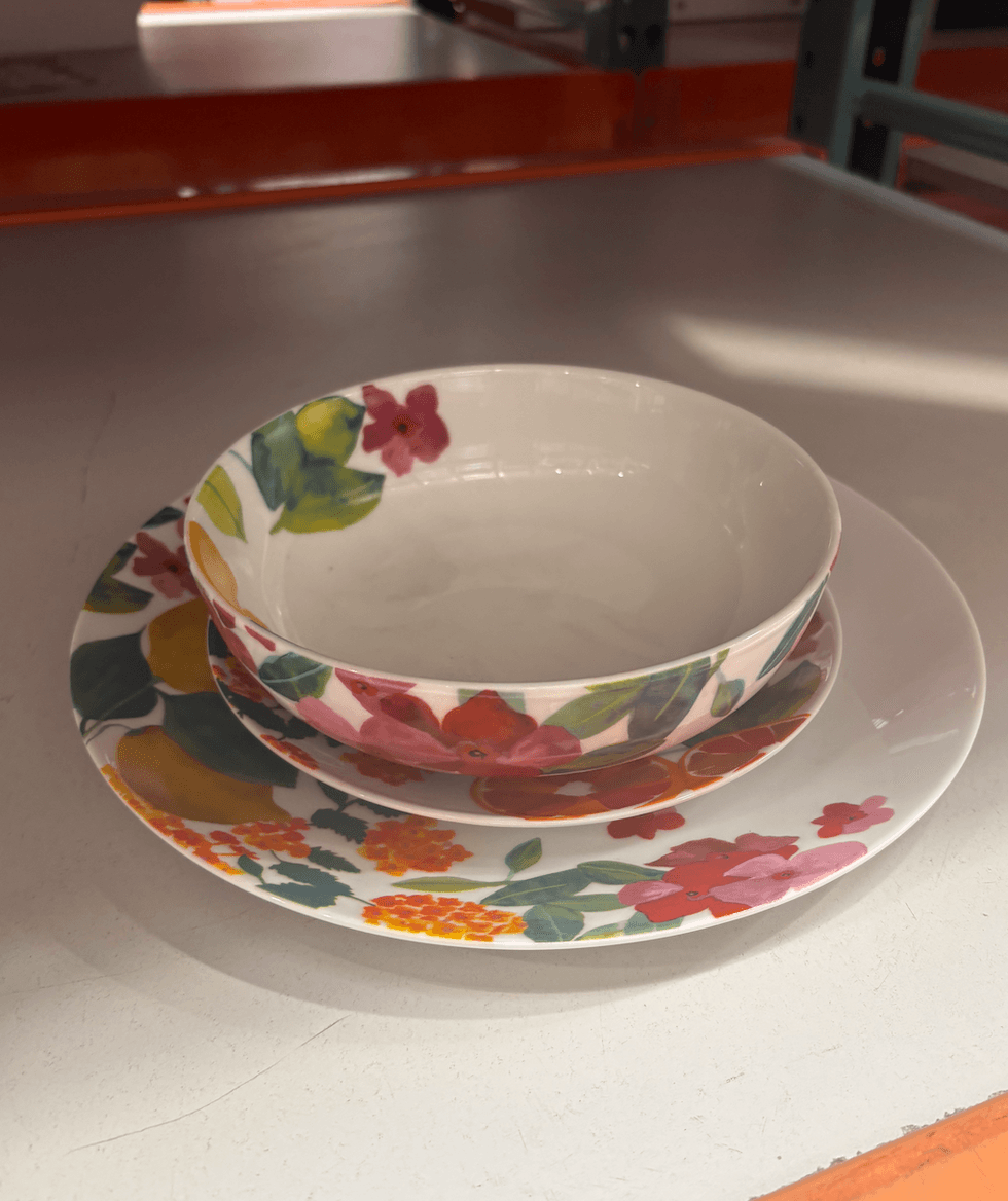 Une assiette, une assiette creuse et un bol blancs d\u00e9cor\u00e9s de fleurs roses, de feuilles vertes et d'agrumes color\u00e9s au Costco.