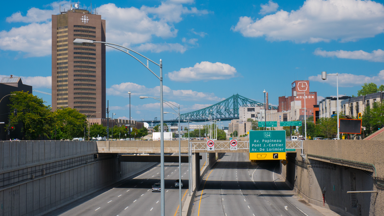 Une autoroute à Montréal avec vue sur la tour de Radio-Canada, l'usine de Molson et le pont Jacques-Cartier.