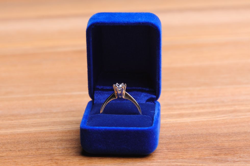 Une bague de fian\u00e7ailles dans une bo\u00eete de velours bleue sur une table en bois