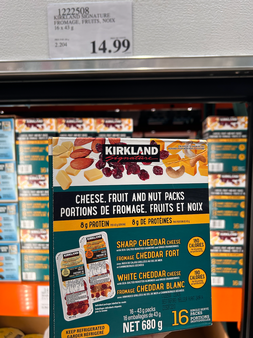 Une boite de portions de fromage, fruits et noix de \u200bKirkland Signature devant un r\u00e9frig\u00e9rateur du Costco.