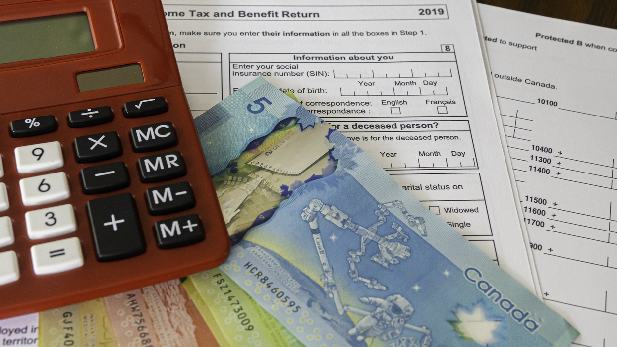 Une calculatrice par-dessus des billets d'argent et des formulaires d'impôt.