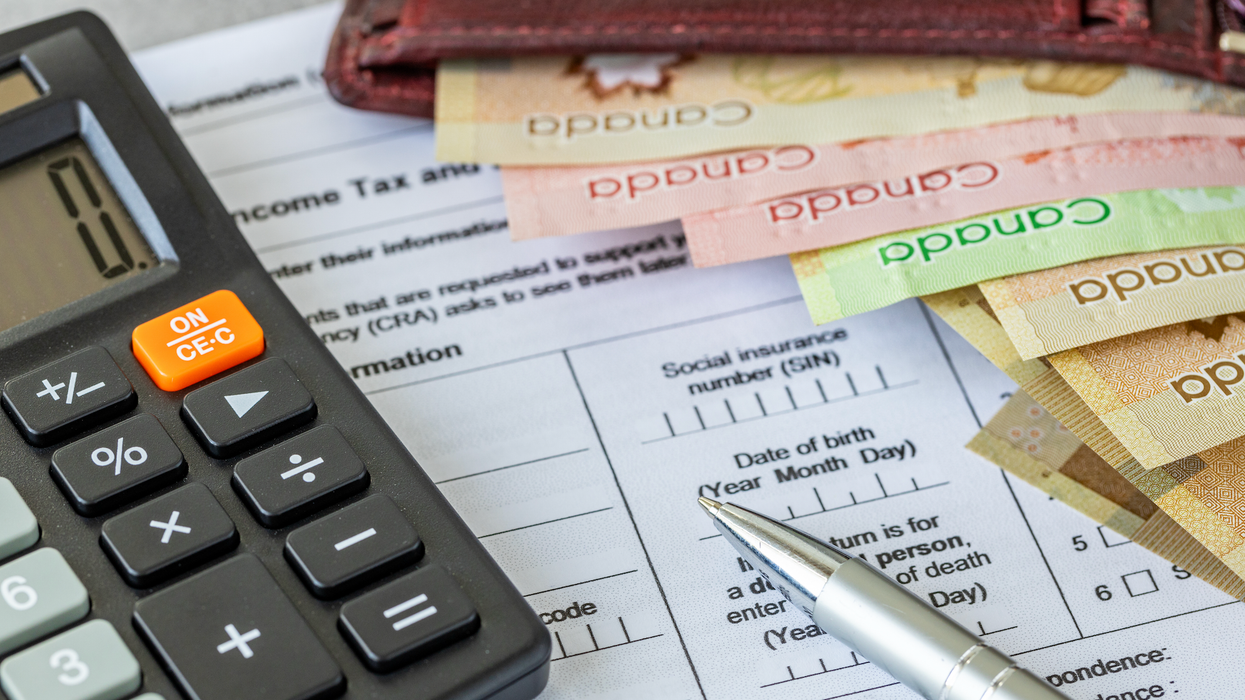 Une calculatrice, un crayon et des billets d'argent sur une déclaration de revenu.