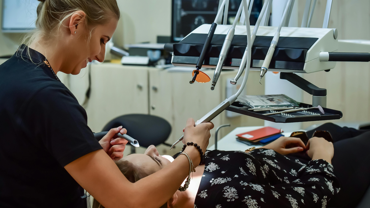 Une dentiste utilise des outils pour traiter une patiente allongée.