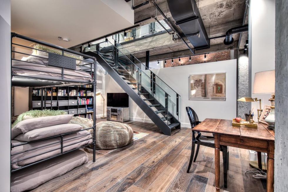 Une des chambres du condominium luxueux avec un grand lit, un escalier et une petite table de bureau avec chaise.