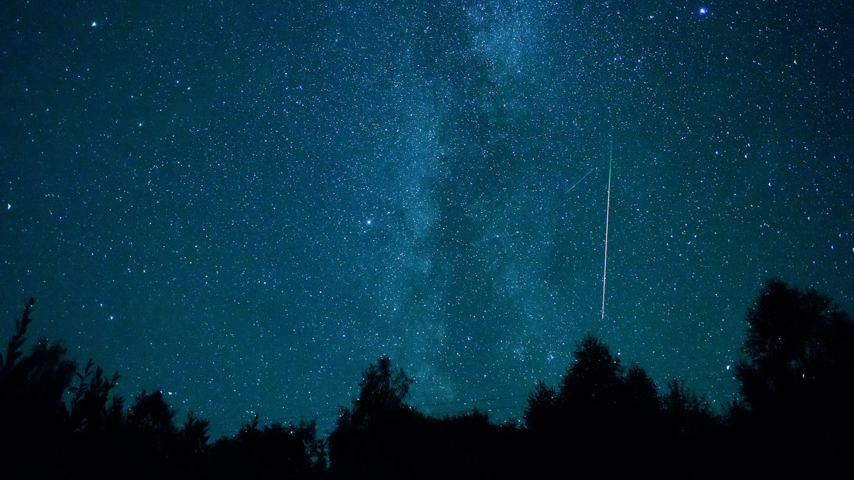 Une étoile filante dans un ciel bleu émeraude étoilé.