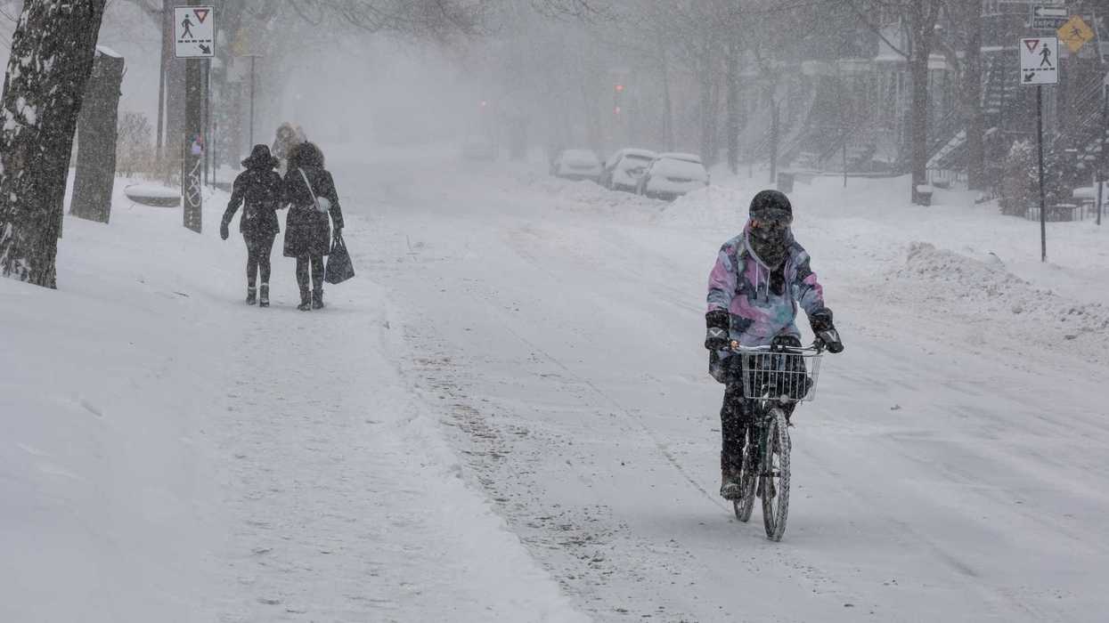 Une femme à vélo durant une tempête de neige.