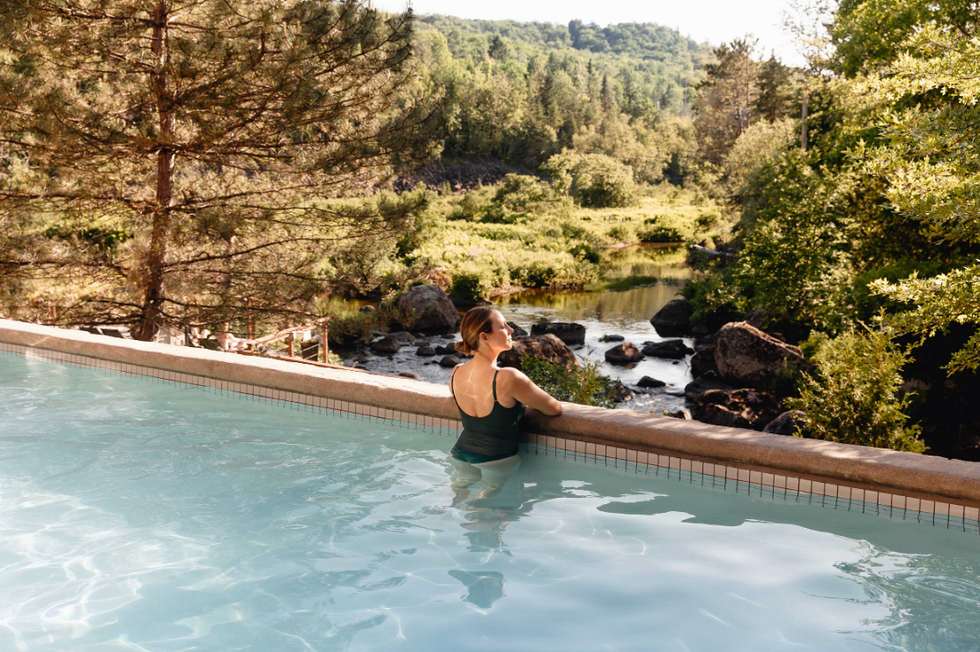 Une femme dans un bassin qui surplombe la nature au spa.