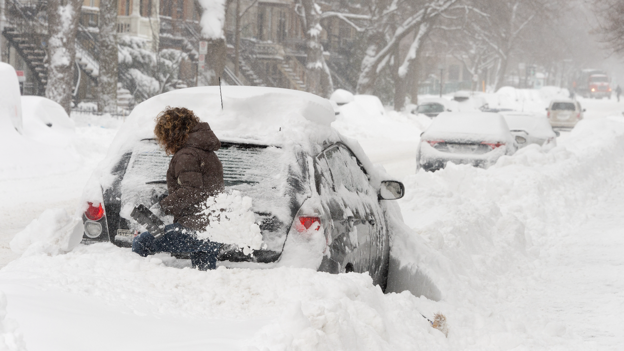Une femme déneige sa voiture après la tempête de neige.