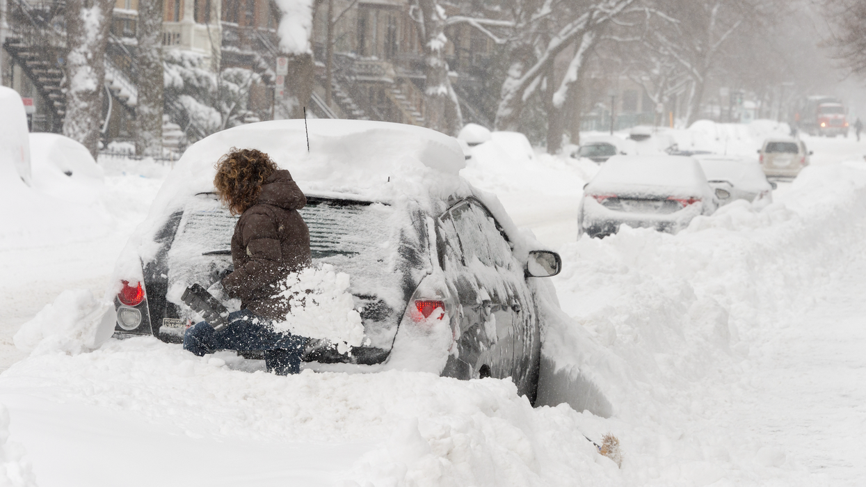 Une femme déneige sa voiture après la tempête de neige.
