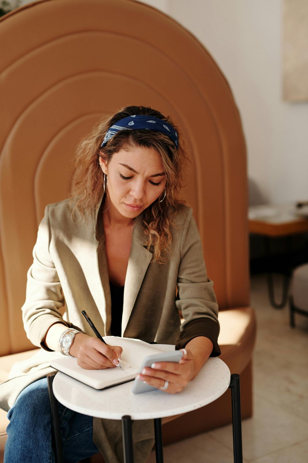 Une femme en blazer marron assise sur une chaise.