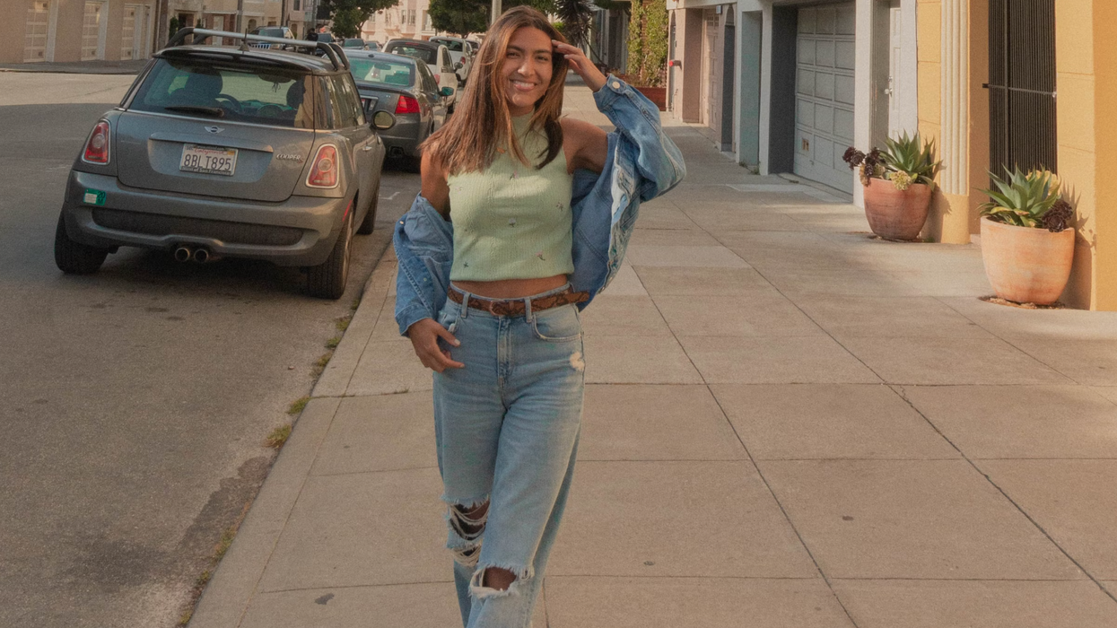 Une femme en veste en jeans bleu et en jeans troués debout sur le trottoir pendant la journée