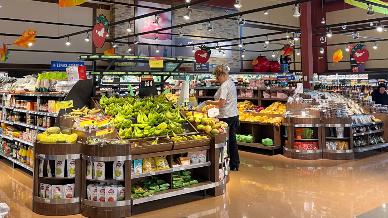 Une femme magasine dans le rayon des fruits et légumes au IGA.