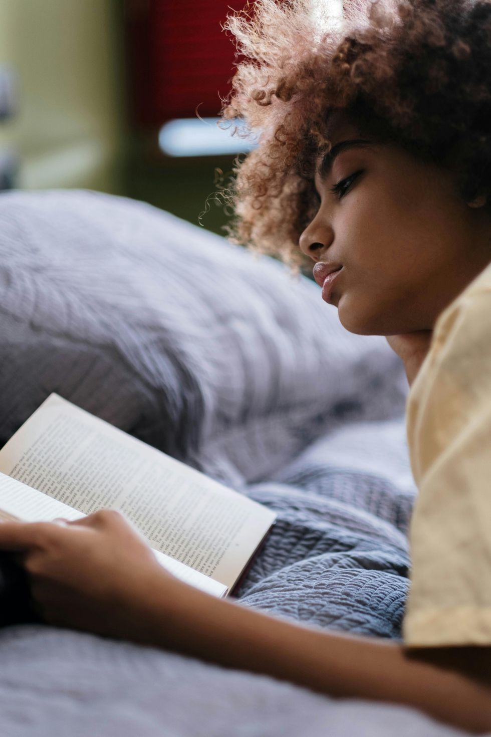 Une femme qui lit un livre dans son lit.