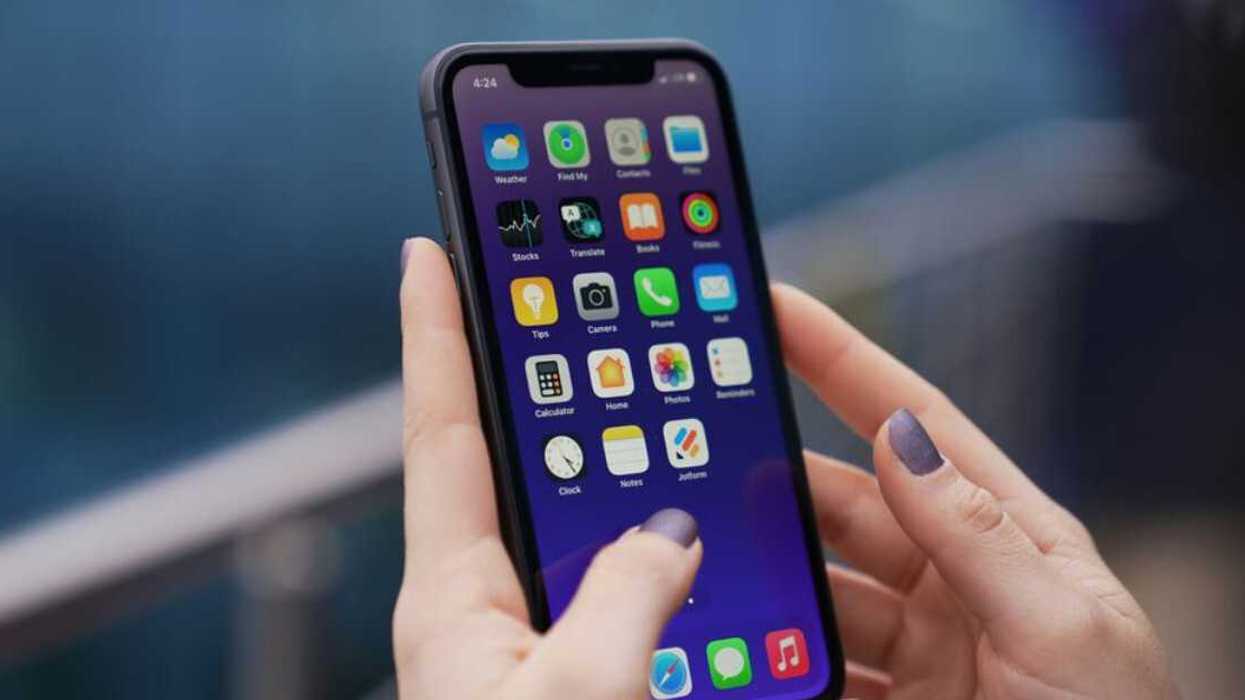 Une femme qui tient un téléphone cellulaire dans ses mains.