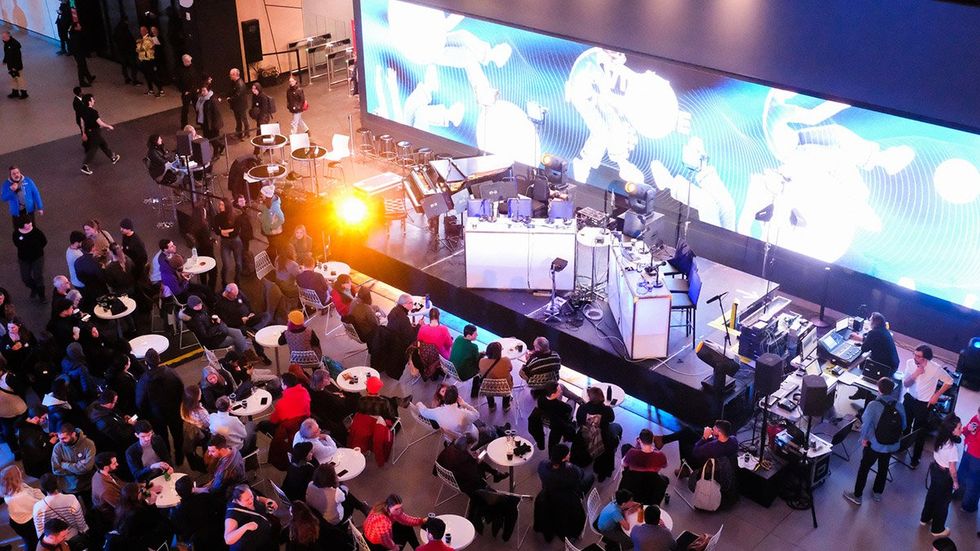 Une foule devant une sc\u00e8ne et un \u00e9cran lumineux.