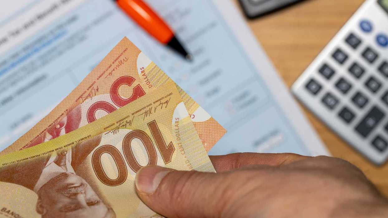 Une main d'homme qui tient de l'argent canadien.
